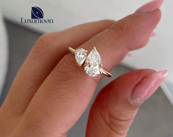 May include: A gold ring with two pear-shaped diamonds. The diamonds are set in a prong setting and are surrounded by a thin band of gold.