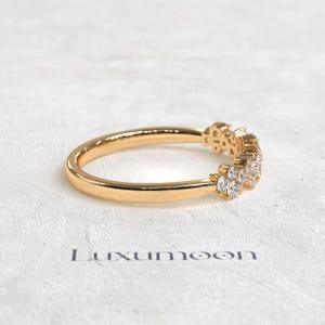 May include: A gold ring featuring a cluster of small, clear, round-cut stones set along one side of the band. The word Luxumoon is printed in dark lettering below the ring. The band has a smooth, polished finish and a rounded profile.
