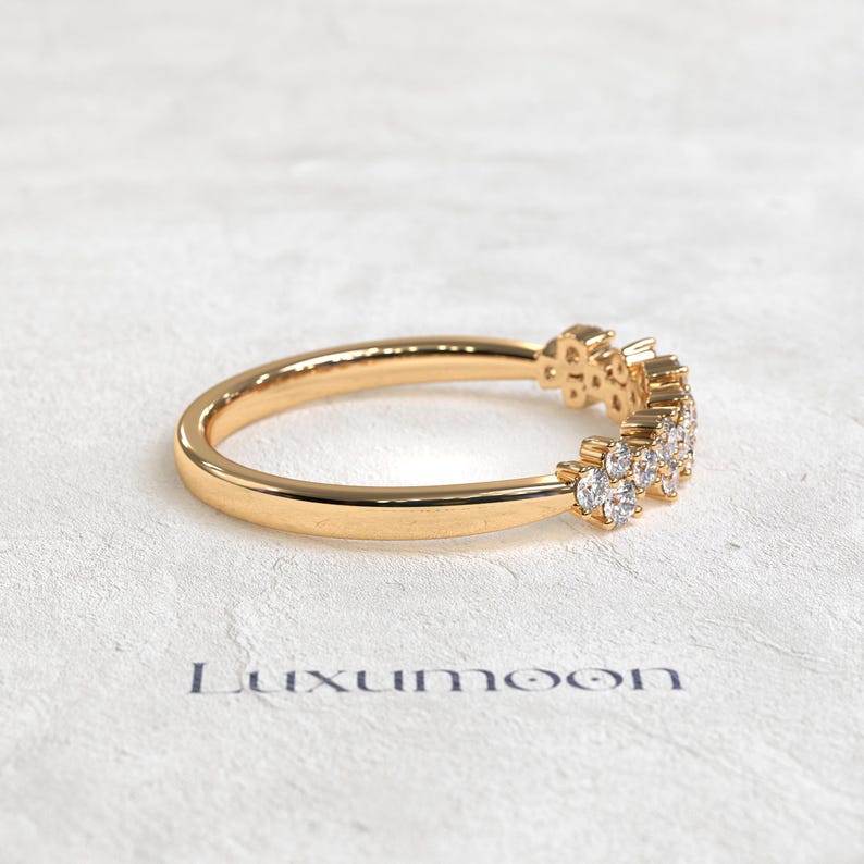 May include: A gold ring featuring a cluster of small, clear, round-cut stones set along one side of the band. The word Luxumoon is printed in dark lettering below the ring. The band has a smooth, polished finish and a rounded profile.