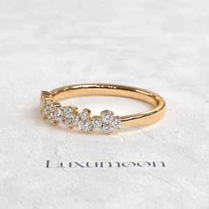 May include: A gold ring featuring a cluster of small, round, clear stones set along the top half of the band. The band has a smooth, polished finish. The word Luxumoon is printed in dark letters below the ring on the textured surface.