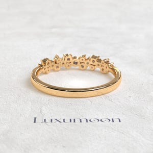 May include: A gold ring featuring a cluster of small, clear stones set along the top half of the band. The band is smooth and polished, with a rounded profile. Below the ring, the word Luxumoon is printed in a dark, sans-serif font.
