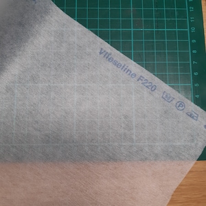 May include: White fusible interfacing with the text "Vlieseline F220" and washing instructions.