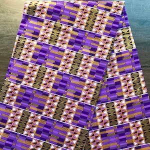 May include: Purple and gold fabric with a geometric pattern. The fabric has a shiny finish and is perfect for making clothing or accessories.