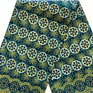 Puede incluir: Tela turquesa con un patrón repetitivo de flores estilizadas amarillas, azules y blancas. La tela tiene un brillo sutil.