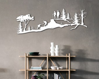 Puede incluir: Arte de pared de metal blanco que representa una silueta de una cordillera con árboles y excursionistas. El arte está montado en una pared gris sobre un estante de madera con libros, jarrones y plantas.