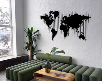 Può includere: Una decorazione murale a mappa del mondo in metallo nero è montata su una parete bianca strutturata. Un divano verde e un tavolino in legno con gambe in metallo sono di fronte al muro. Una pianta verde alta è a sinistra del divano.