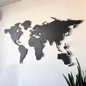 May include: A dark grey metal world map fixed to a white wall. The map shows the continents and countries in detail. This wall art is a decorative item suitable for a home or office setting.