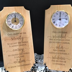 May include: Two wooden plaques with clocks, featuring inspirational quotes. One clock has Roman numerals and the other has Arabic numerals. The first plaque reads "God, grant me the serenity..." The second plaque reads "Dios Concédeme serenidad..."
