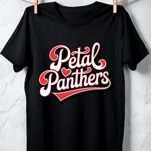 May include: Black t-shirt with the words "Petal Panthers" in a white, red, and pink retro design. The text includes a heart symbol. The shirt is hanging on a clothesline.