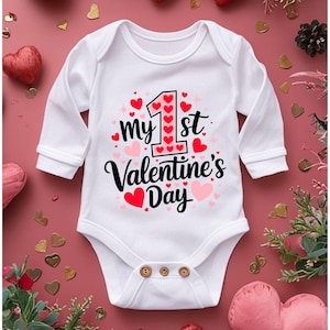 May include: White long-sleeved baby onesie with a red and pink graphic that says "my 1st Valentine's Day" with a large number one surrounded by hearts.