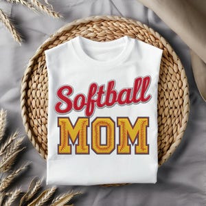 Puede incluir: Camiseta blanca con el texto "Softball Mom" en rojo y amarillo con un diseño de puntada de béisbol.