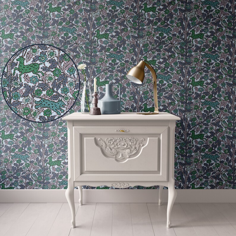 May include: A white painted wooden nightstand with a single drawer and ornate carvings. The nightstand has cabriole legs and sits in front of a wall covered in a floral wallpaper with a repeating pattern of green and pink stylized animals.