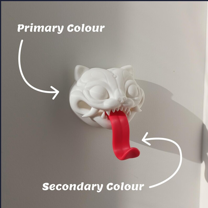 May include: A white cat-shaped wall hook with a red tongue. The cat has sharp teeth and is mounted on a wall. The text "Primary Colour" and "Secondary Colour" are in the image.