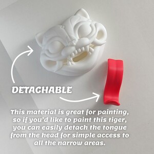 May include: A white, detachable tiger head with a red tongue. The tiger head has detailed features and sharp teeth. The text "DETACHABLE" is visible, along with instructions for painting the tiger.
