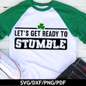 May include: A white t-shirt with green sleeves and a black and white graphic that says "Let's Get Ready To Stumble". A green shamrock is above the text.