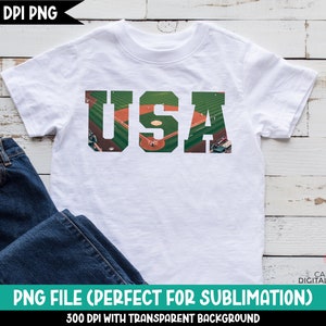 May include: White t-shirt with a graphic of the letters "USA" made up of a baseball field with players and a green outfield.