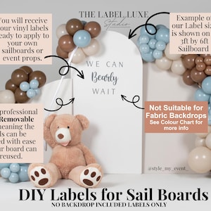 May include: A white arched sailboard featuring the text WE CAN Bearly WAIT in dark lettering. The display is decorated with a balloon garland in shades of brown, blue, and cream, and a plush teddy bear sits in front of the board.
