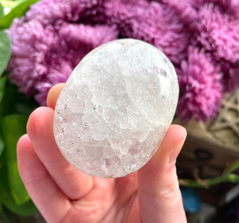 May include: A clear, white, oval-shaped crystal with a textured surface. The crystal is about the size of a golf ball.