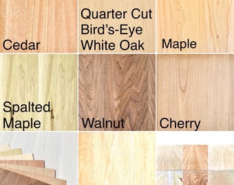 May include: A grid of wood veneer samples labeled Cedar, Quarter Cut Bird's-Eye White Oak, Maple, Spalted Maple, Walnut, Cherry, and Birch. The image displays various wood grain patterns, textures, and natural light brown to cream tones.