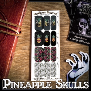 May include: A set of 12 nail decals featuring pineapple skulls with black and white backgrounds. The decals are packaged in a white card with the text "CLAWS AND STILETTOS NAIL DECALS" and "CLAWSANDSTILETTOS.COM".