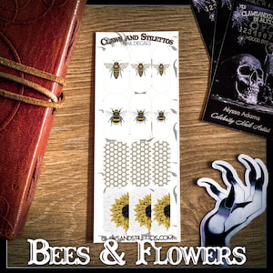 May include: A sheet of nail decals featuring bees and sunflowers. The decals are white with a gold honeycomb pattern. The text "CLAWS AND STILETTOS" and "BEES & FLOWERS" are printed on the sheet.