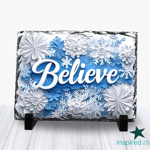 May include: A slate plaque with a blue and white paper flower design and the word "Believe" in white lettering.
