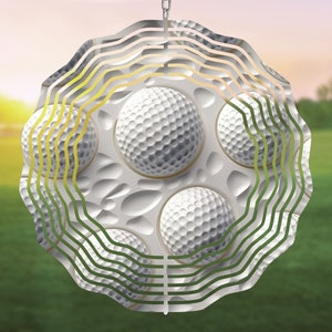 May include: A metal wind spinner with a circular design featuring multiple golf balls. The spinner has a layered, wavy pattern in shades of green and gold.