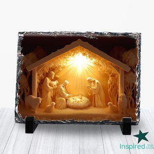 Peut inclure: Une scène de nativité rectangulaire et éclairée, sculptée dans une pierre sombre. La scène représente Marie, Joseph et l'enfant Jésus dans une crèche, avec des moutons et d'autres personnages. La lumière brille derrière les personnages, créant une lueur chaleureuse.