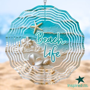 May include: A blue and white metal wind spinner with the words "Beach Life" in white text. The spinner features a seashell, starfish, and flowers.