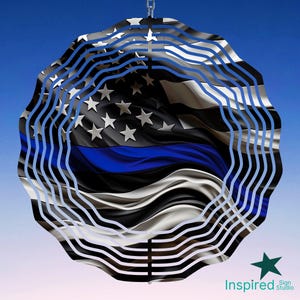 May include: A metal wind spinner with a blue and black American flag design with a thin blue line. The wind spinner has a circular shape with multiple layers of metal.