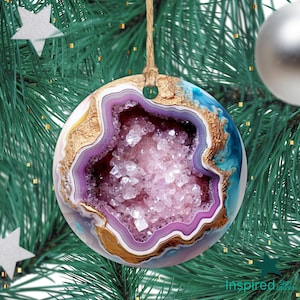 May include: A pink and purple agate geode ornament with gold accents. The geode is a natural crystal formation with a hollow center filled with sparkling crystals. The ornament is perfect for adding a touch of nature to your holiday decor.