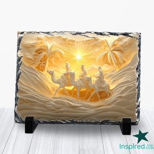 Puede incluir: Escultura en relieve rectangular blanquecina que representa a tres figuras montadas en camellos en una escena desértica, con palmeras y un sol brillante. La escultura está sobre un soporte negro, y los bordes tienen un borde áspero y oscuro.