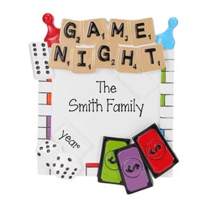 May include: A white ceramic ornament with a game board design. The ornament features a banner with the words "GAME NIGHT" spelled out in black letters on tan tiles. The ornament also includes a space for a personalized name, "The Smith Family", and a space for a year.