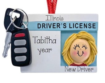 May include: A rectangular ornament shaped like an Illinois driver's license with a red hanging ribbon. It features the text Illinois DRIVER'S LICENSE, Tabitha, year, and New Driver. A 3D blonde character head and a black car key fob are attached.
