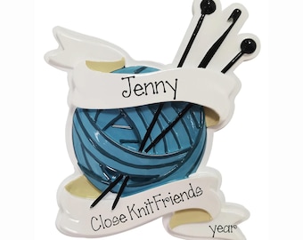 May include: A decorative ornament featuring a blue yarn ball with black knitting needles and a crochet hook. Two white banners are draped over the yarn, with the text Jenny, Close Knit Friends, and year printed in black script lettering.