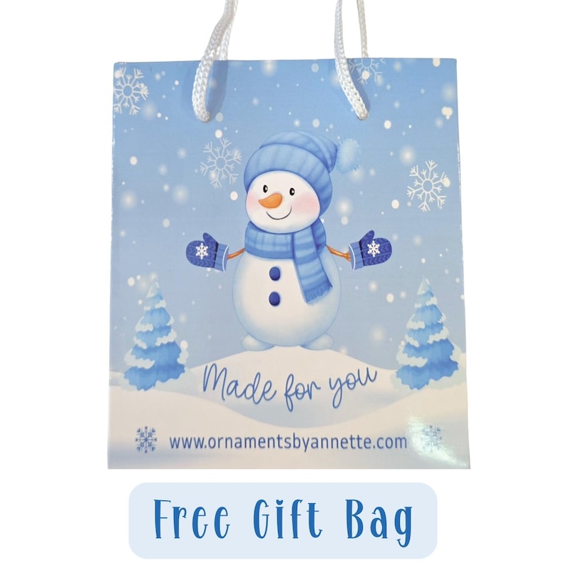A blue gift bag with a snowman illustration and snowflakes, along with the text "Made for you" and a website address.