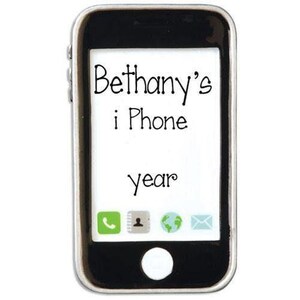 May include: A black smartphone-shaped ornament with a white screen displaying the text Bethany's i Phone and year. The screen features four small icons at the bottom representing a phone, contacts, globe, and envelope. It has a silver border.