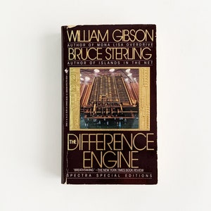 May include: A brown book cover with gold lettering. The title is "The Difference Engine" by William Gibson and Bruce Sterling. The cover features a photo of a large, intricate machine.