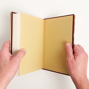 May include: An open book with a burgundy cover and cream colored pages. The book is open to a blank page.