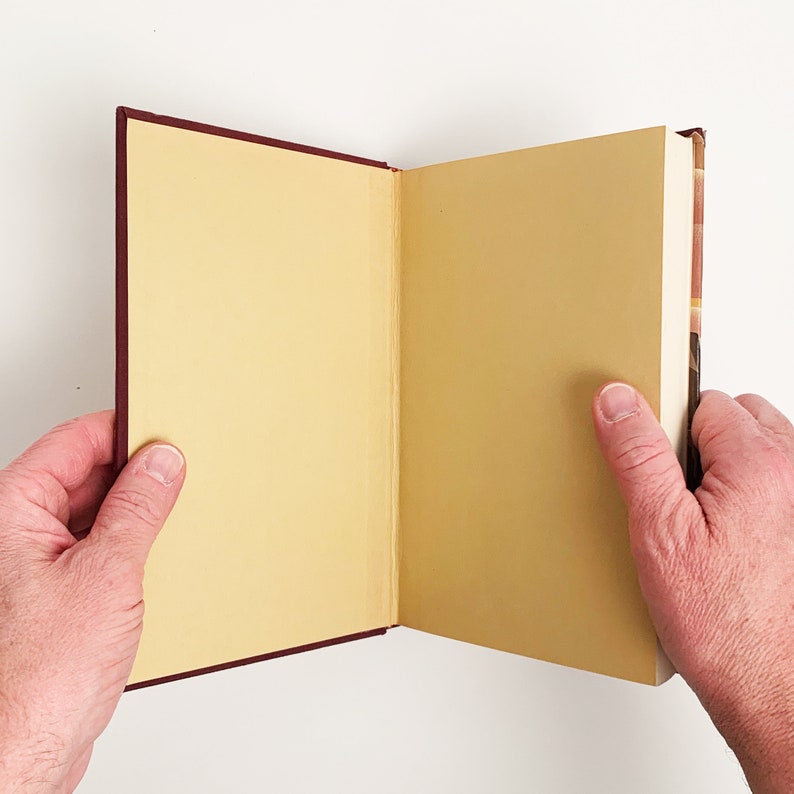 May include: A burgundy hardcover book with a yellowed page open to a blank page.