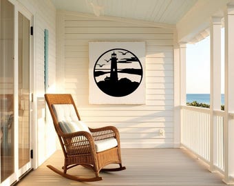 May include: A white rocking chair sits on a wooden porch overlooking the ocean. A black and white silhouette of a lighthouse with birds flying overhead is on the wall behind the chair.