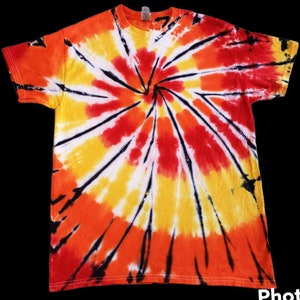 Puede incluir: Una camiseta tie-dye con un diseño en espiral en tonos naranja, amarillo, rojo y negro.