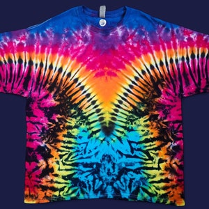 Puede incluir: Una camiseta tie-dye con un patrón de arcoíris y remolinos negros. La camiseta tiene cuello en V y mangas cortas.