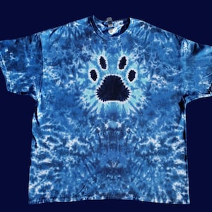 Puede incluir: Una camiseta azul tie-dye con una huella de pata negra en el centro.