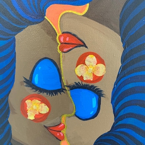 以下が含まれることがあります： 青い髪と大きな青い目を持つ顔のカラフルな絵。顔には赤い唇とオレンジ色のアクセントがあります。黄色い花が付いた2つの赤い円が顔にあります。背景はニュートラルブラウンです。