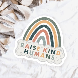 May include: A sticker featuring a rainbow design and the text "Raise Kind Humans" within a cloud shape.
