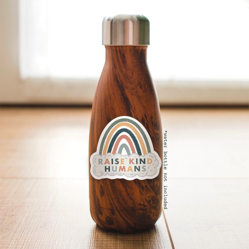 May include: A brown water bottle with a sticker that says "Raise Kind Humans" and features a rainbow with a cloud.