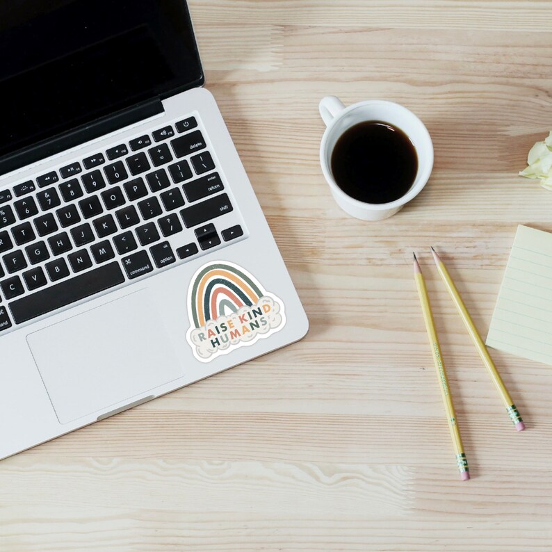 May include: A sticker featuring a rainbow design and the text "Raise Kind Humans" within a cloud shape.
