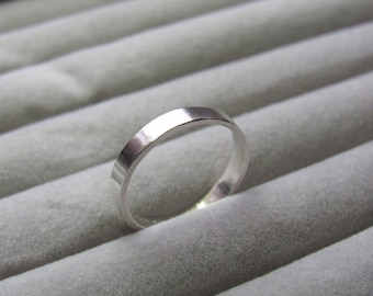 Peut inclure: Une bague simple en argent, présentée sur un fond de velours gris.
