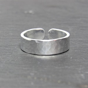 May include: A silver hammered adjustable ring. The ring is made of metal and has a smooth, hammered finish.